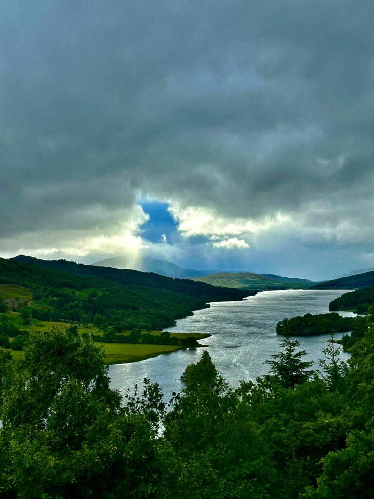 Lac paisible entouré de collines verdoyantes sous un ciel orageux